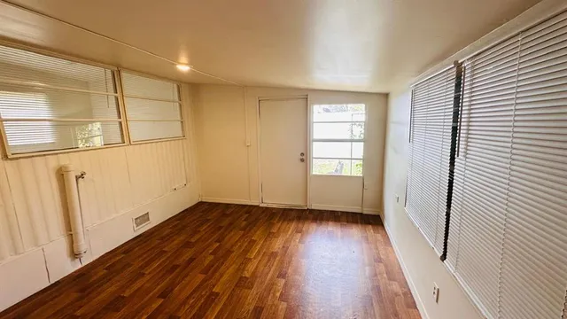 a view of an empty room with wooden floor and a window
