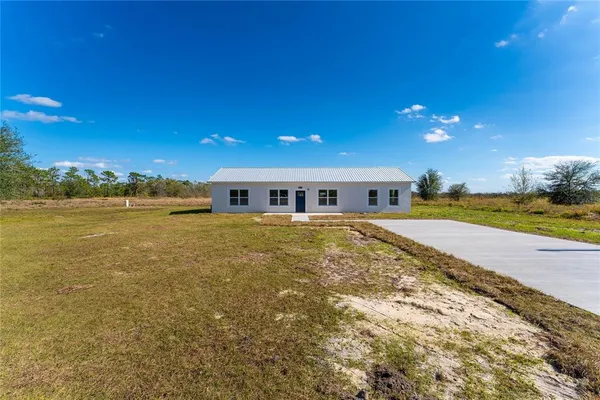 a front view of house with yard and ocean