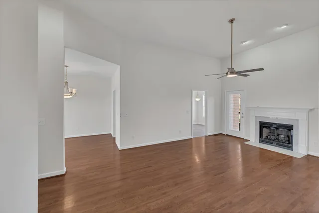 a view of an empty room with wooden floor fireplace and a window