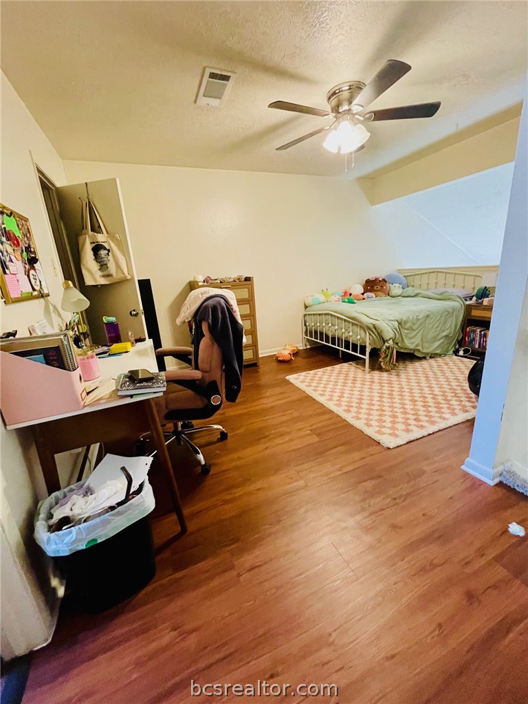 922 Spring Loop, Unit A College Station, TX 77840 - Photo 15 of 20 Bedroom with visible vents, a textured ceiling, a ceiling fan, and wood finished floors