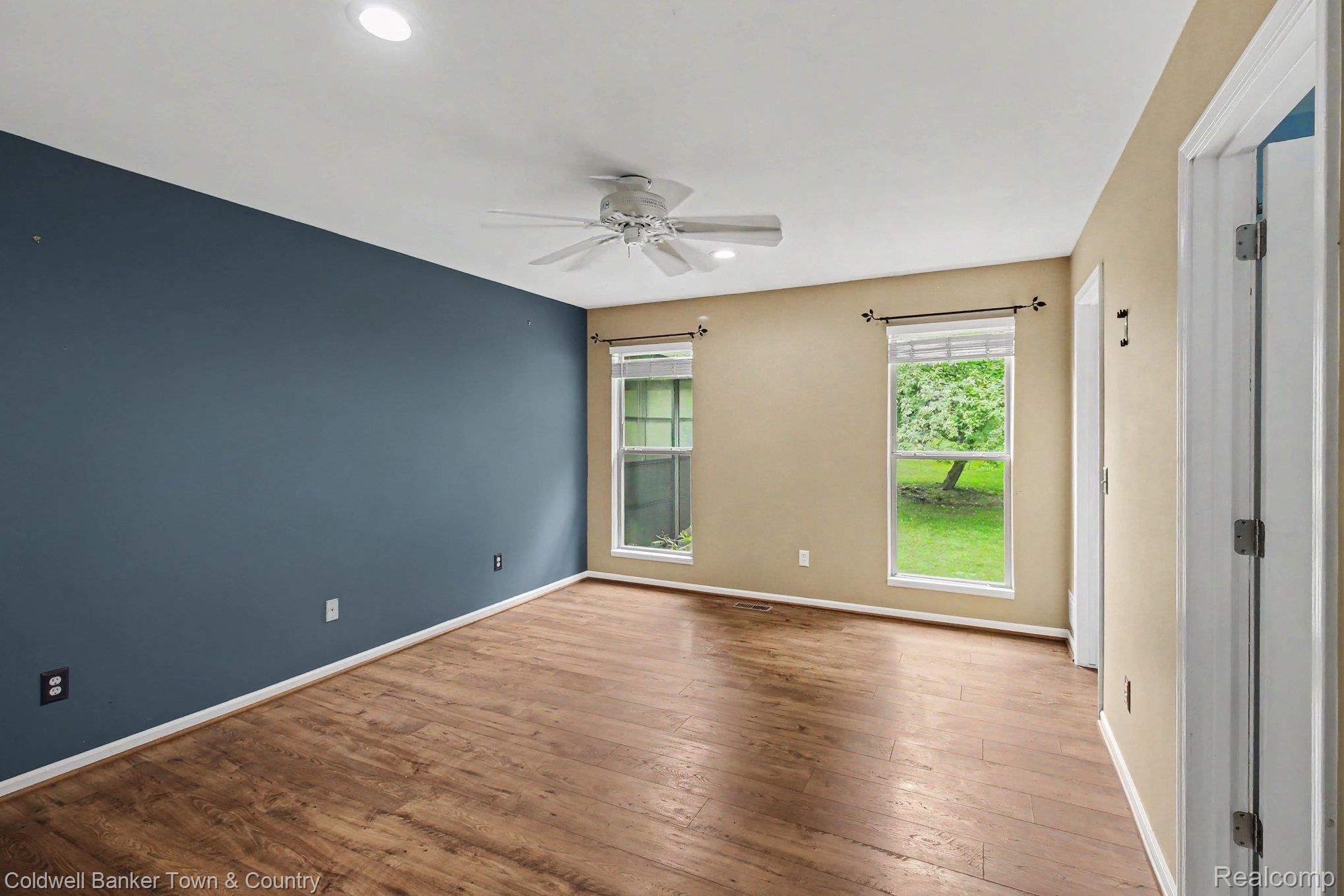 332 Triangle Lake Road Howell, MI 48843 - Photo 11 of 27 Spacious room featuring wood-finish flooring, two large windows, a ceiling fan, and recessed lighting