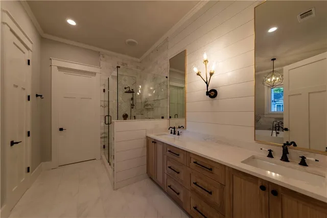 a spacious bathroom with a double vanity sink a large mirror and shower