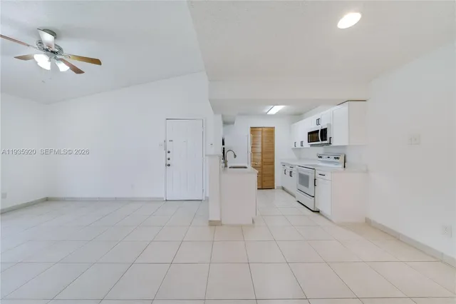 a view of a kitchen with white cabinets and white appliances