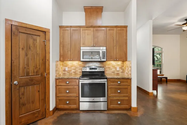 a kitchen with stainless steel appliances granite countertop cabinets a sink a island and windows