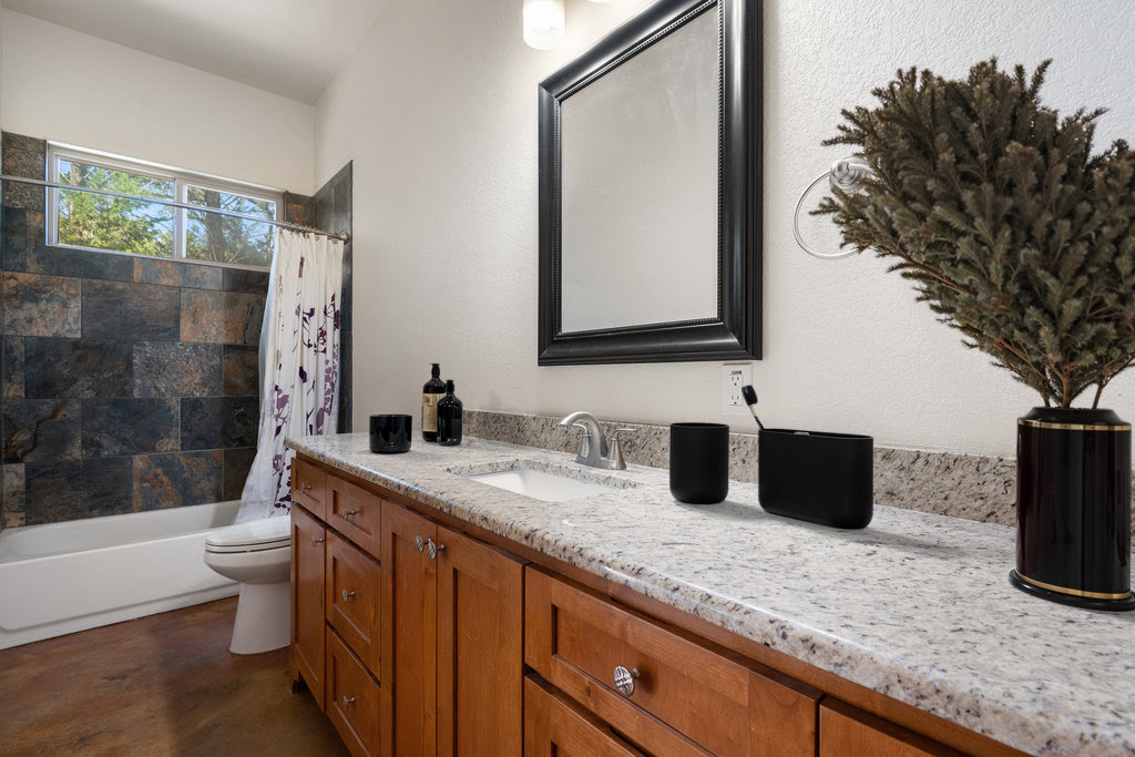 267 Corral Road Smithville, TX 78957 - Photo 34 of 40 a bathroom with a granite countertop sink a toilet a mirror and shower
