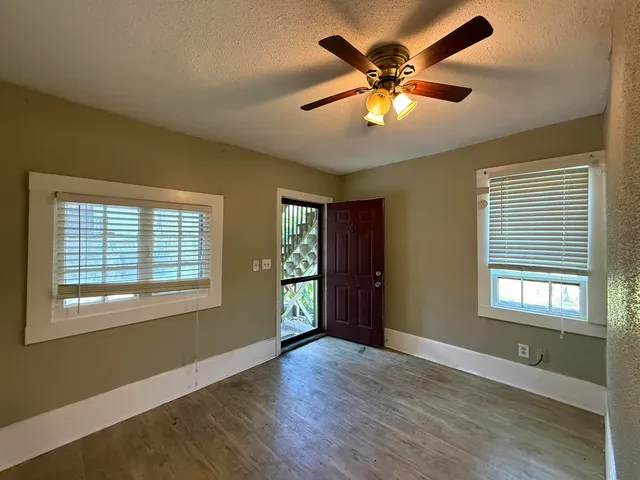 a view of an empty room with window and wooden floor