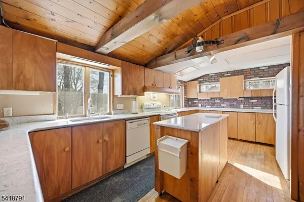 a kitchen with granite countertop wooden cabinets a sink a window and stainless steel appliances