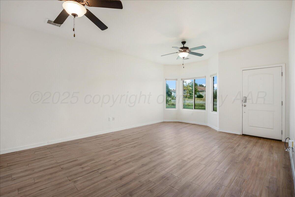 1007 Shiraz Boulevard Amarillo, TX 79124 - Photo 4 of 21 an empty room with wooden floor chandelier fan and windows