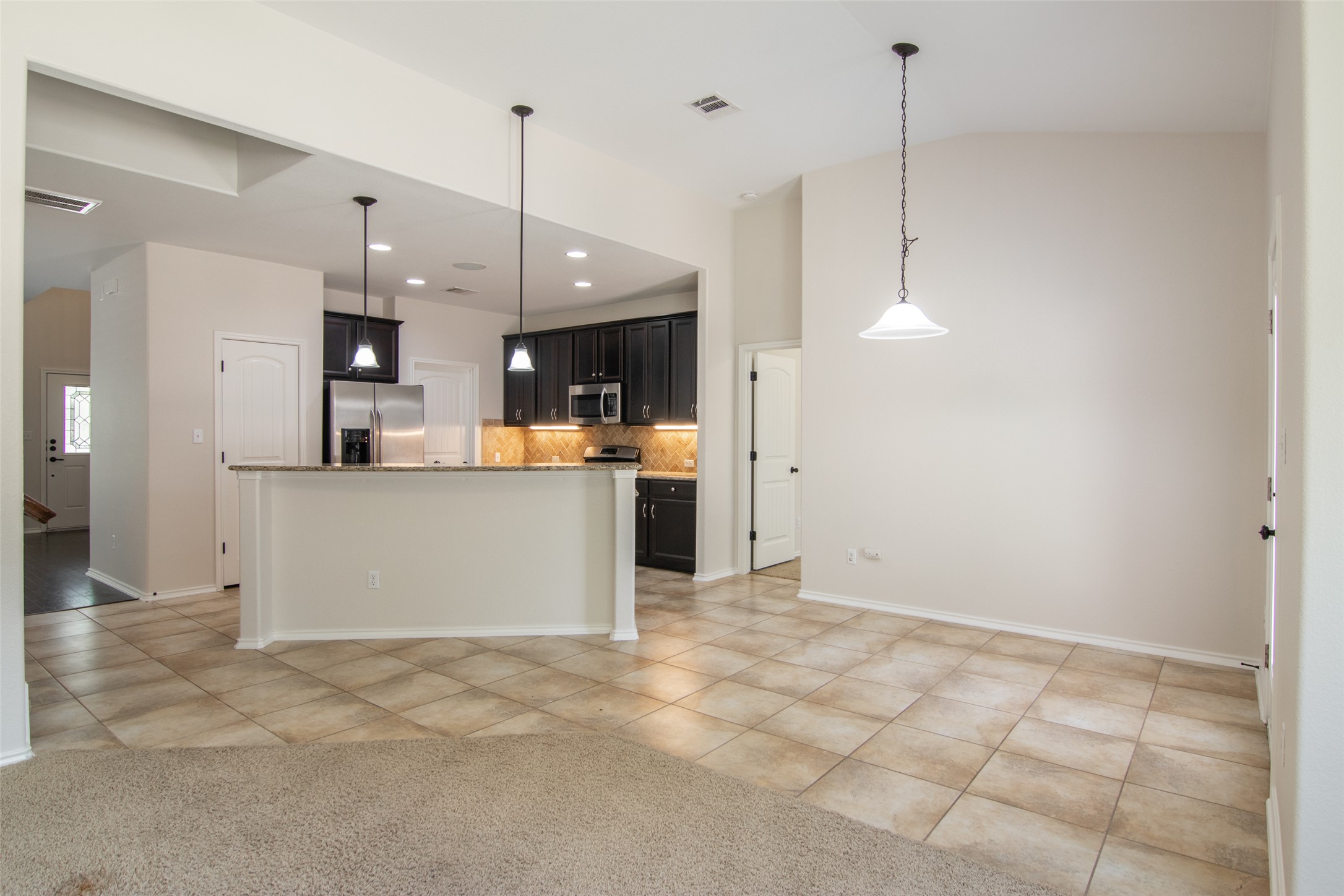 12104 Broten Street Austin, TX 78748 - Photo 31 of 32 An open floorplan seamlessly connects the kitchen and living areas, highlighted by contemporary pendant lighting.