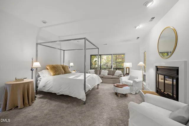 a spacious bedroom with a bed a fireplace and a chandelier