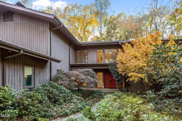 a view of a house with a small yard plants and large tree