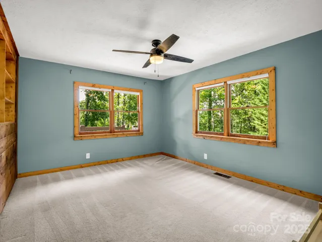an empty room with windows and ceiling fan
