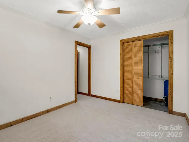 an empty room with closet and a ceiling fan
