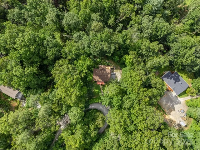an aerial view of residential house with outdoor space and trees all around