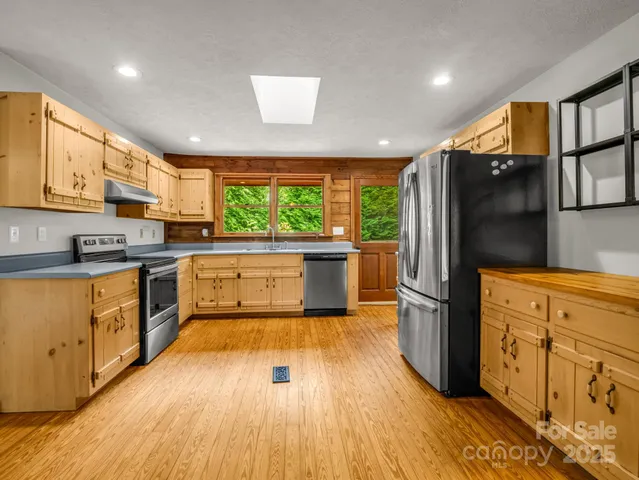 a kitchen with stainless steel appliances wooden floors and wooden cabinets