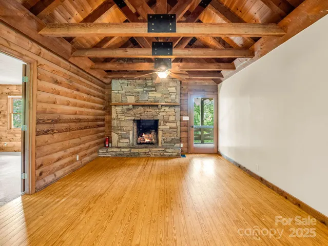 a view of an empty room with wooden floor a fireplace and a window