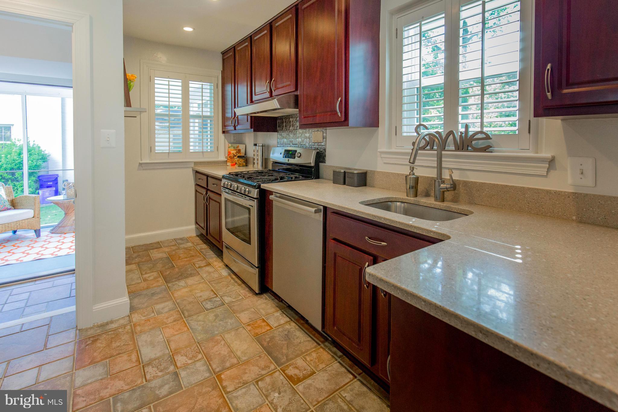 9010 Eton Road Silver Spring, MD 20901 - Photo 13 of 30 a kitchen with stainless steel appliances a sink dishwasher a stove a microwave oven and a dining table with wooden floor