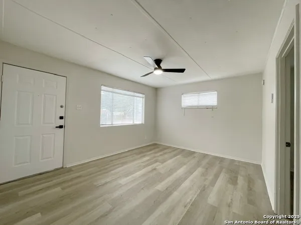 a view of an empty room with wooden floor and a window