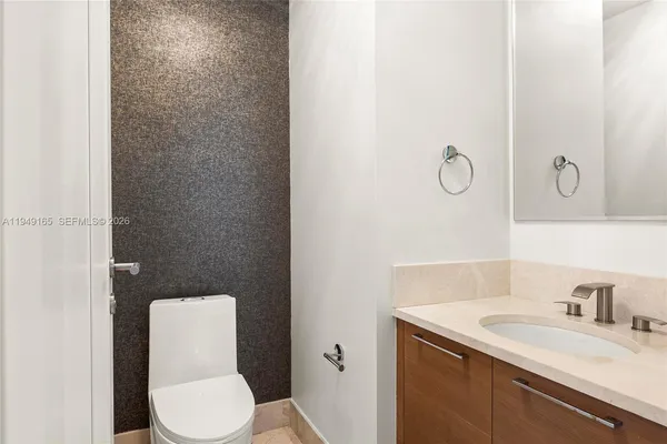 a bathroom with a granite countertop toilet sink and mirror