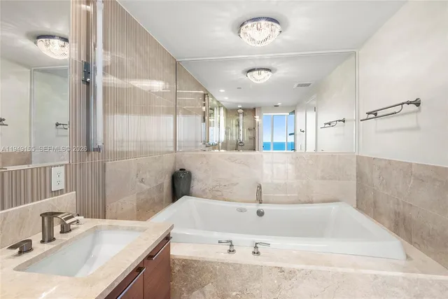 a bathroom with a tub a sink and mirror