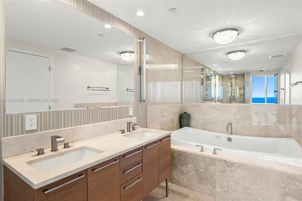 a bathroom with a tub a double vanity sink and mirror