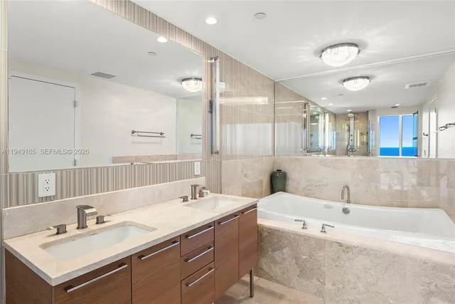 a bathroom with a tub a double vanity sink and mirror