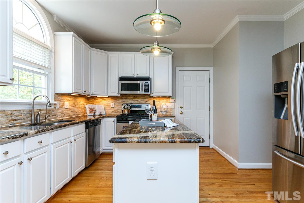 2936 Sunnystone Way Raleigh, NC 27613 - Photo 3 of 29 a kitchen with kitchen island granite countertop a sink appliances cabinets and a counter top space