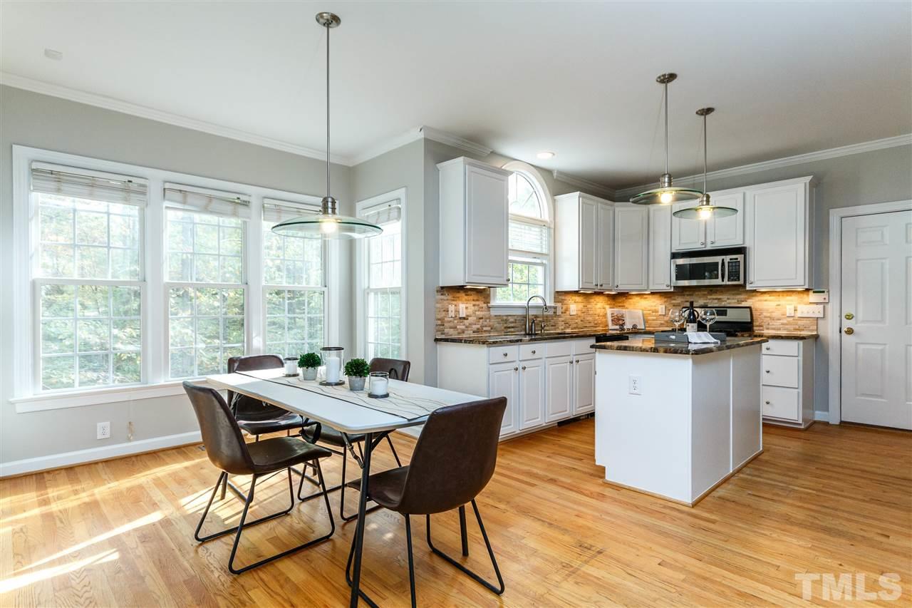 2936 Sunnystone Way Raleigh, NC 27613 - Photo 4 of 29 a kitchen with stainless steel appliances granite countertop wooden floor dining table and chairs