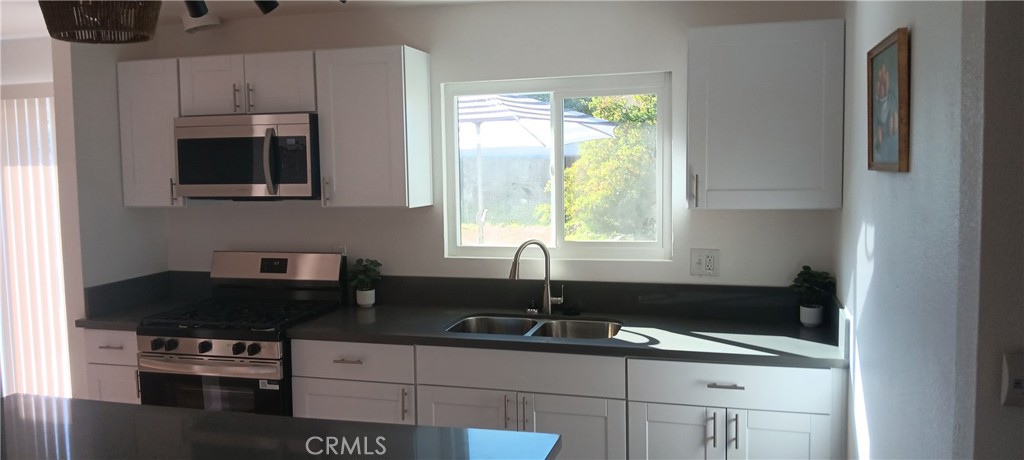 1022 Ruby Drive Perris, CA 92571 - Photo 3 of 27 a kitchen with granite countertop a sink stove and refrigerator