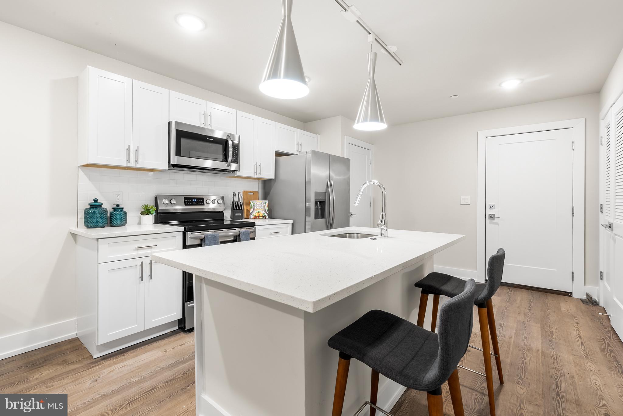 214 Vine Street, Unit 104 Philadelphia, PA 19106 - Photo 2 of 35 a kitchen with stainless steel appliances kitchen island a wooden floor and white cabinets