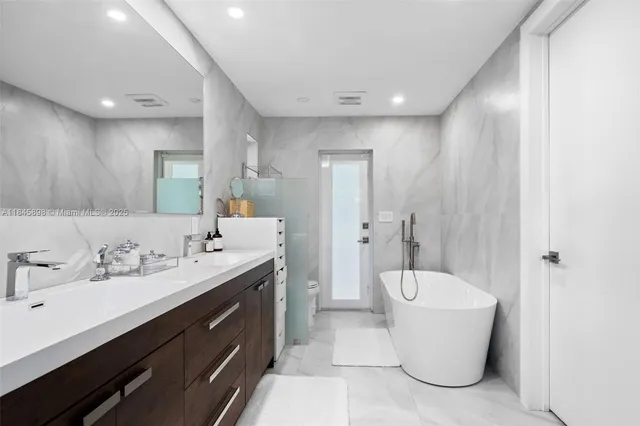 a spacious bathroom with a double vanity sink mirror and bathtub