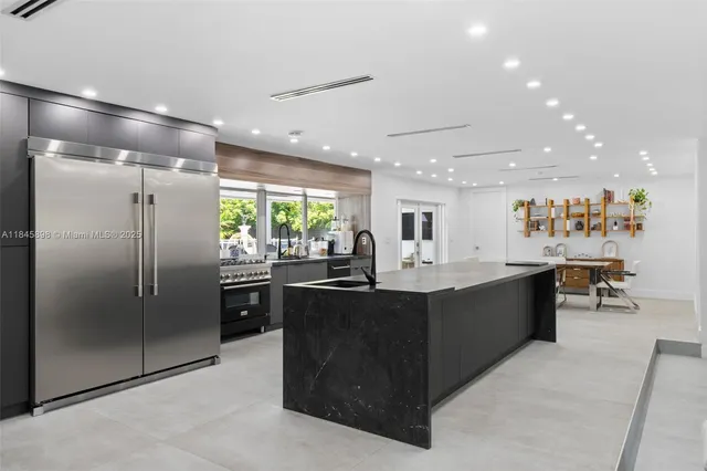 a kitchen with stainless steel appliances granite countertop a refrigerator a sink a stove and a refrigerator