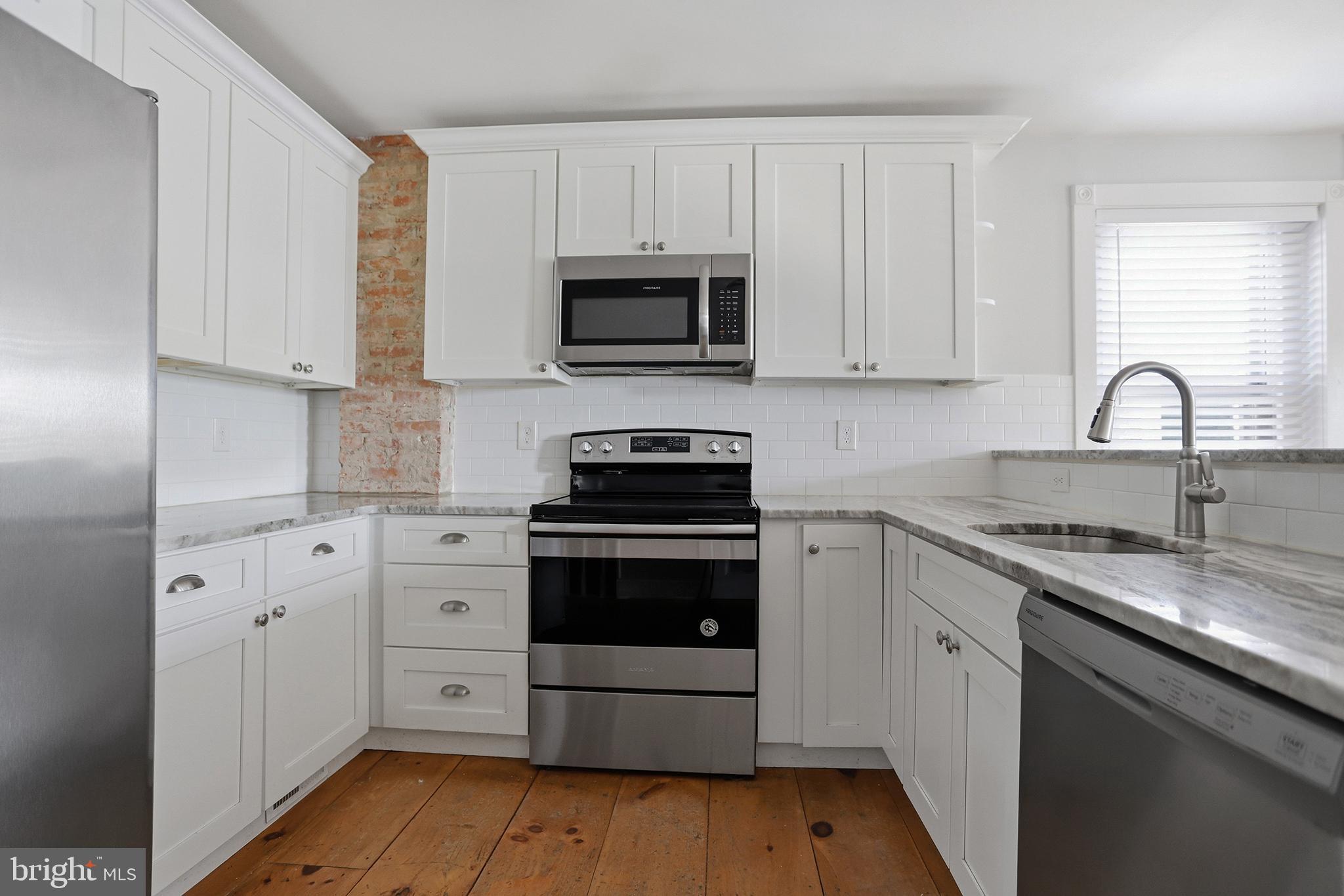 33 East Front Street Media, PA 19063 - Photo 6 of 11 a kitchen with granite countertop a sink and a stove top oven with wooden floor
