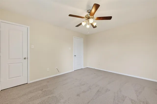 an empty room with a chandelier fan and a wooden floor