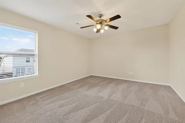 a view of an empty room with chandelier fan and a window