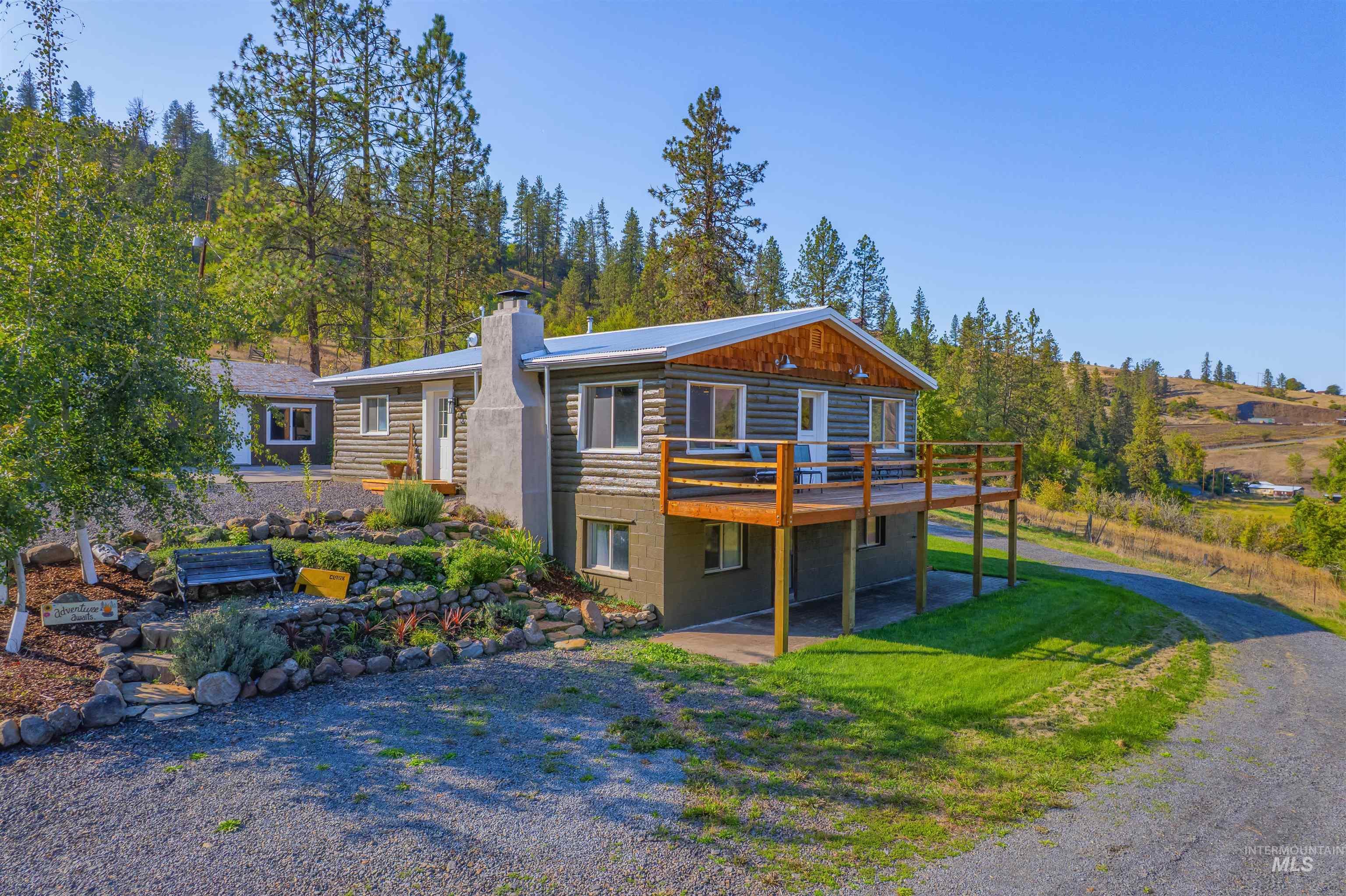 View of front of property featuring a wooden deck, a chimney, and a front lawn