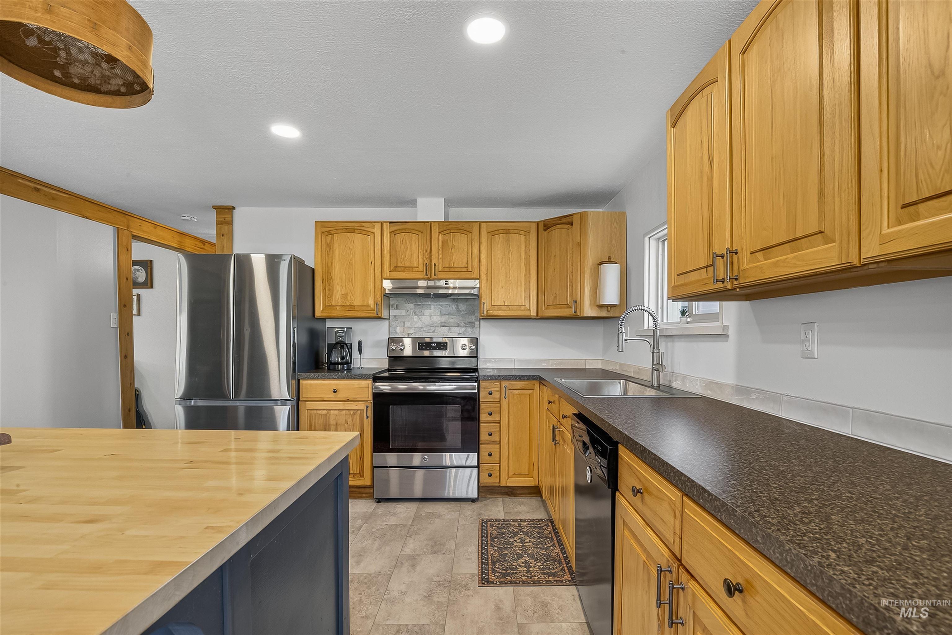 2157 Lukes Gulch Road Stites, ID 83552 - Photo 16 of 50 Kitchen with appliances with stainless steel finishes, tasteful backsplash, recessed lighting, brown cabinets, and under cabinet range hood