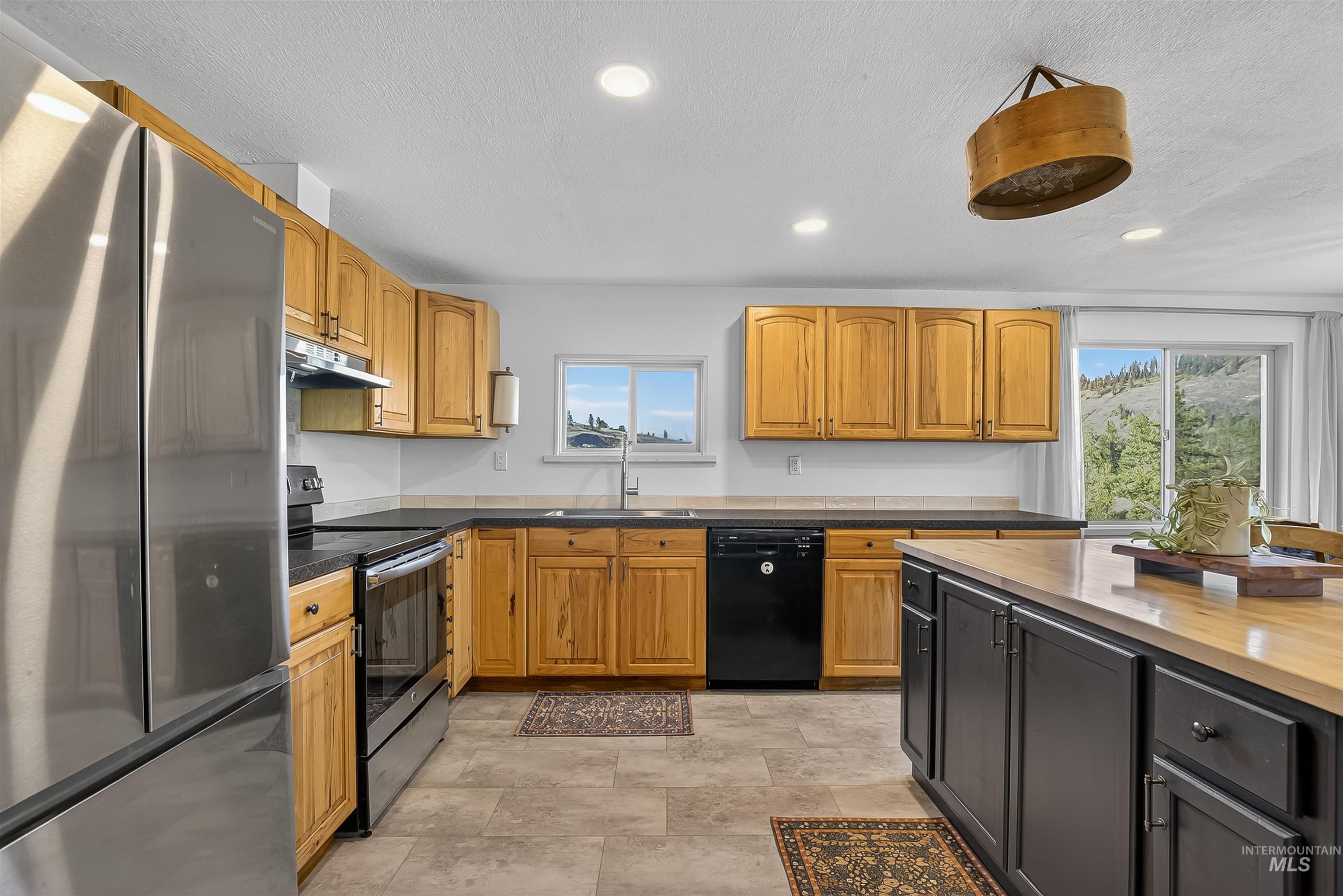 2157 Lukes Gulch Road Stites, ID 83552 - Photo 17 of 50 Kitchen with appliances with stainless steel finishes, butcher block countertops, brown cabinets, a textured ceiling, and dark cabinets