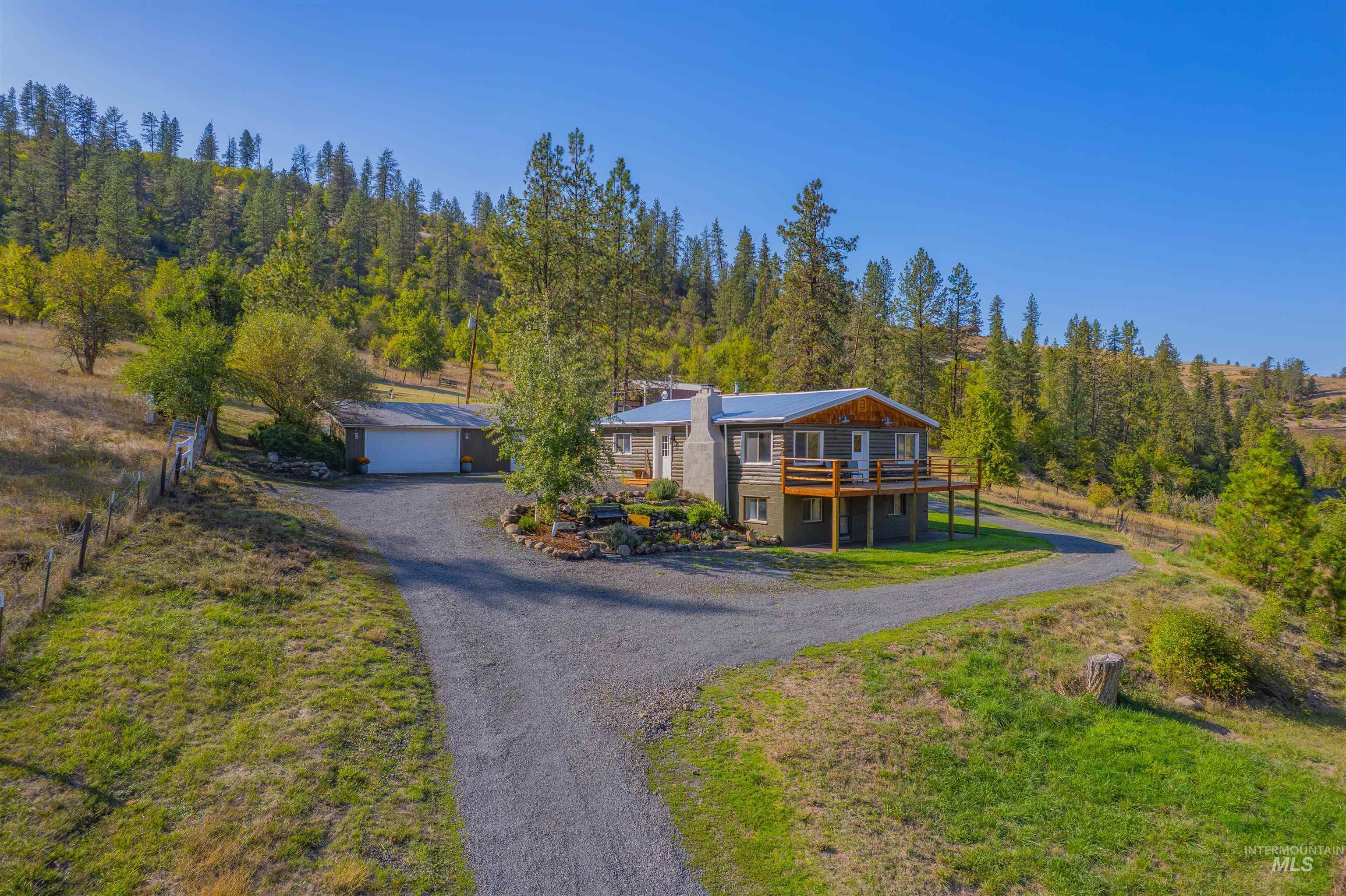 2157 Lukes Gulch Road Stites, ID 83552 - Photo 50 of 50 Modern home featuring a wooden deck, driveway, an outdoor structure, a front lawn, and a garage