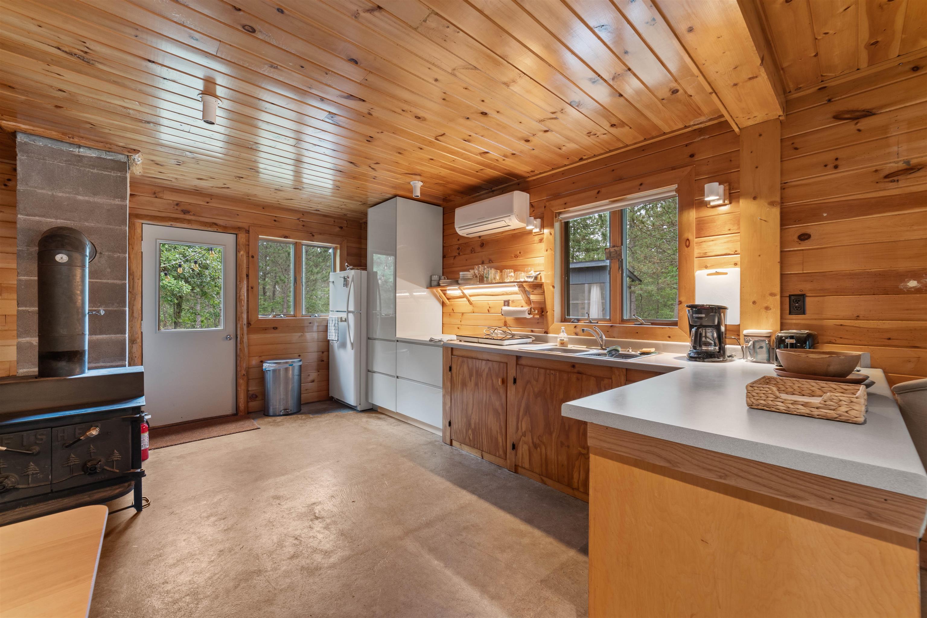 11321 East Town Line Road Solon Springs, WI 54873 - Photo 6 of 31 Kitchen with a wood stove, freestanding refrigerator, a wall mounted AC, plenty of natural light, and wood walls