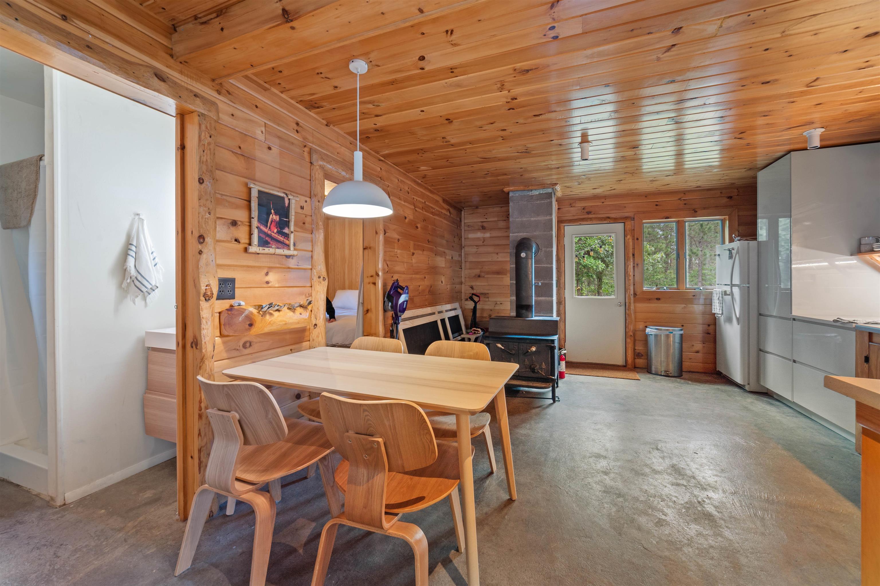 11321 East Town Line Road Solon Springs, WI 54873 - Photo 8 of 31 Dining room with a wood stove, concrete flooring, wooden ceiling, and wooden walls