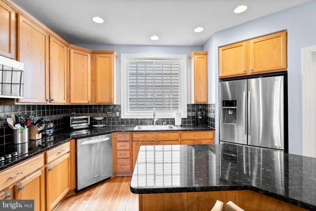 a kitchen with stainless steel appliances granite countertop a refrigerator a sink and dishwasher with wooden floor