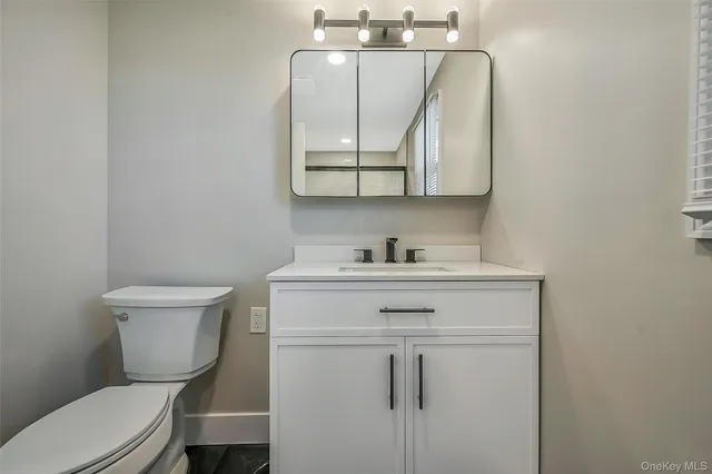 a bathroom with a toilet a sink a vanity and mirror