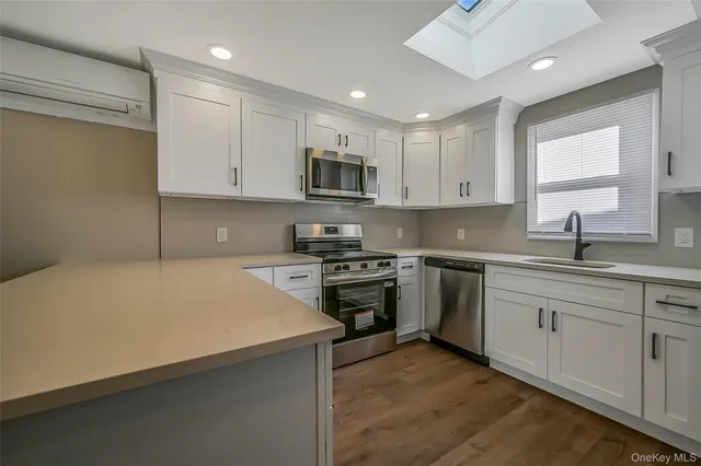 a kitchen with stainless steel appliances granite countertop a sink dishwasher a stove and a refrigerator with wooden floor