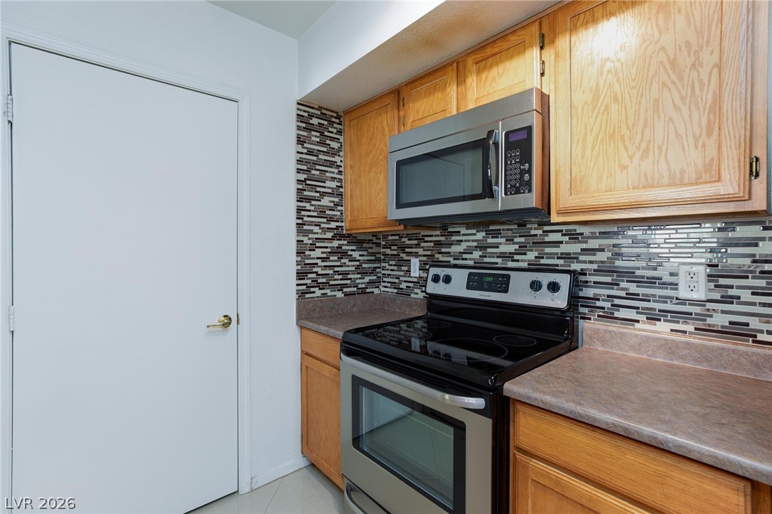 6650 West Warm Springs Road, Unit 2027 Las Vegas, NV 89118 - Photo 12 of 29 This modern kitchen features warm wood cabinetry and a sleek mosaic tile backsplash.