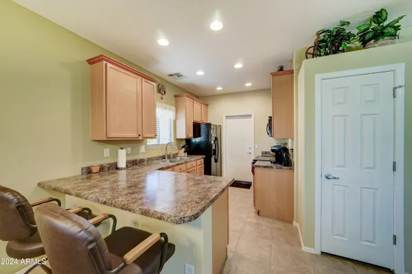 a kitchen with kitchen island granite countertop wooden cabinets and a refrigerator