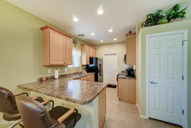 a kitchen with kitchen island granite countertop wooden cabinets and a refrigerator