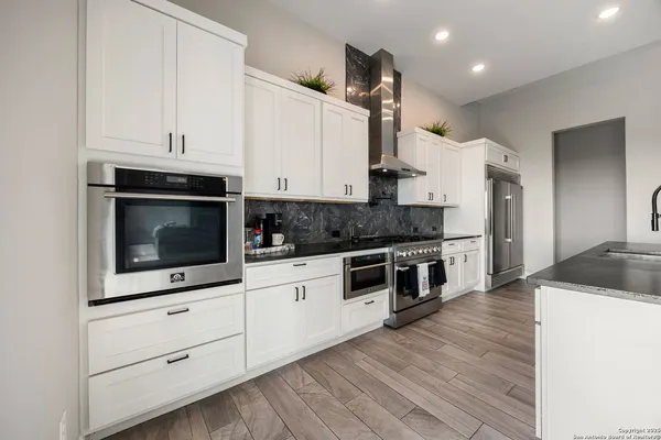 a kitchen with a table chairs a sink dishwasher stove and cabinets with wooden floor