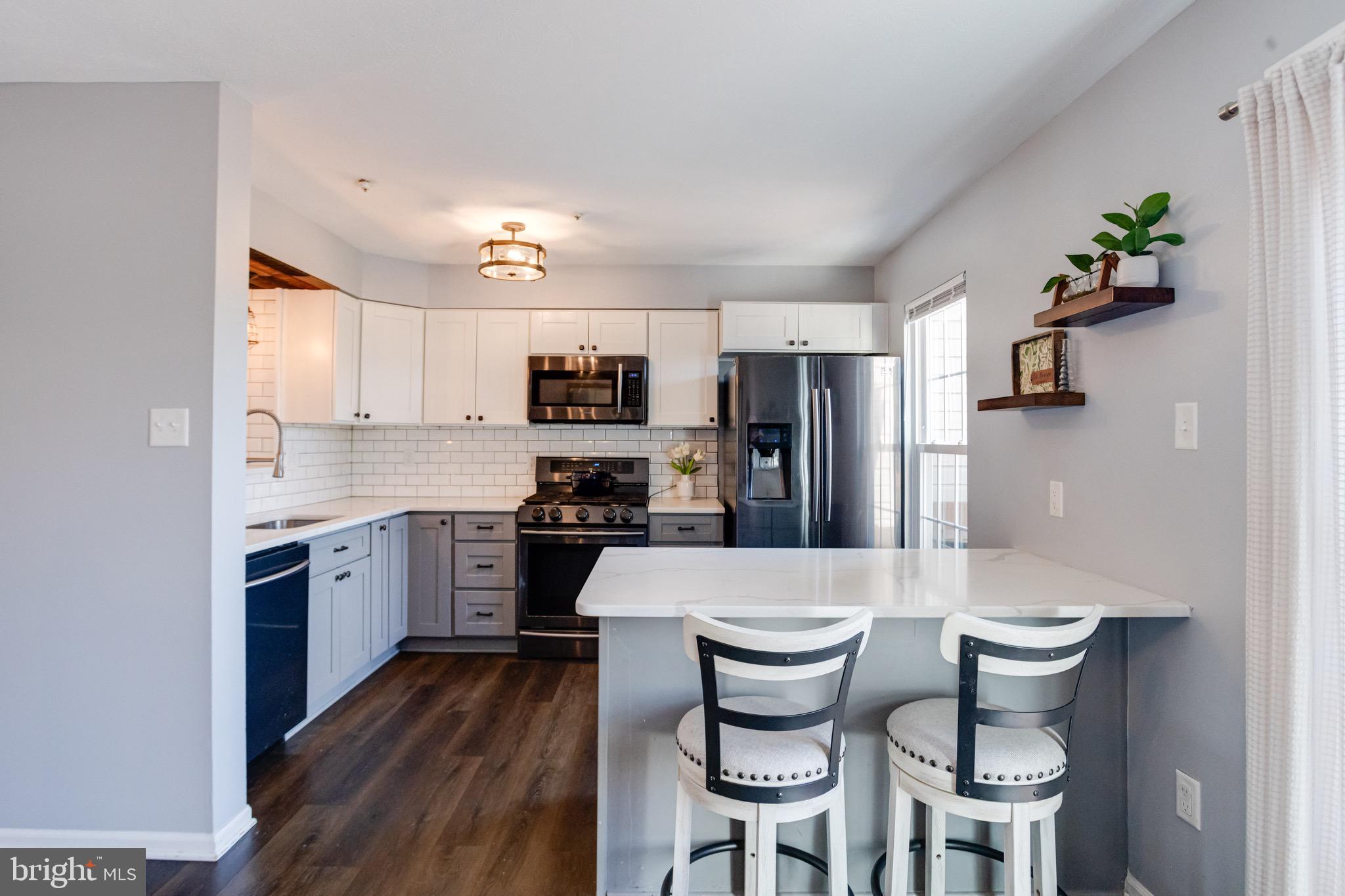 16 Sandview Court Baltimore, MD 21209 - Photo 9 of 58 a kitchen with a refrigerator a stove a sink dishwasher and white cabinets with wooden floor
