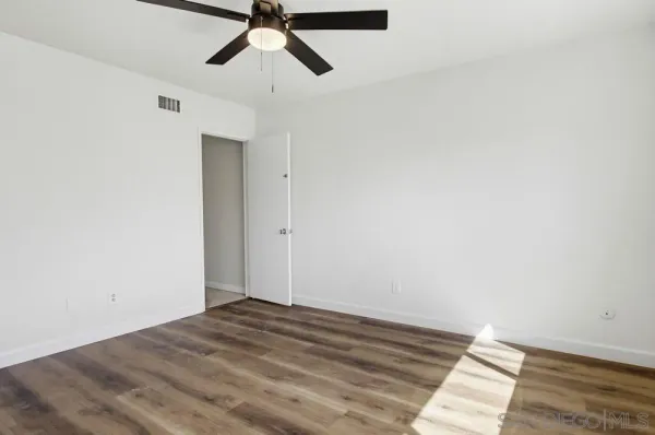 a view of a room with wooden floor and ceiling fan